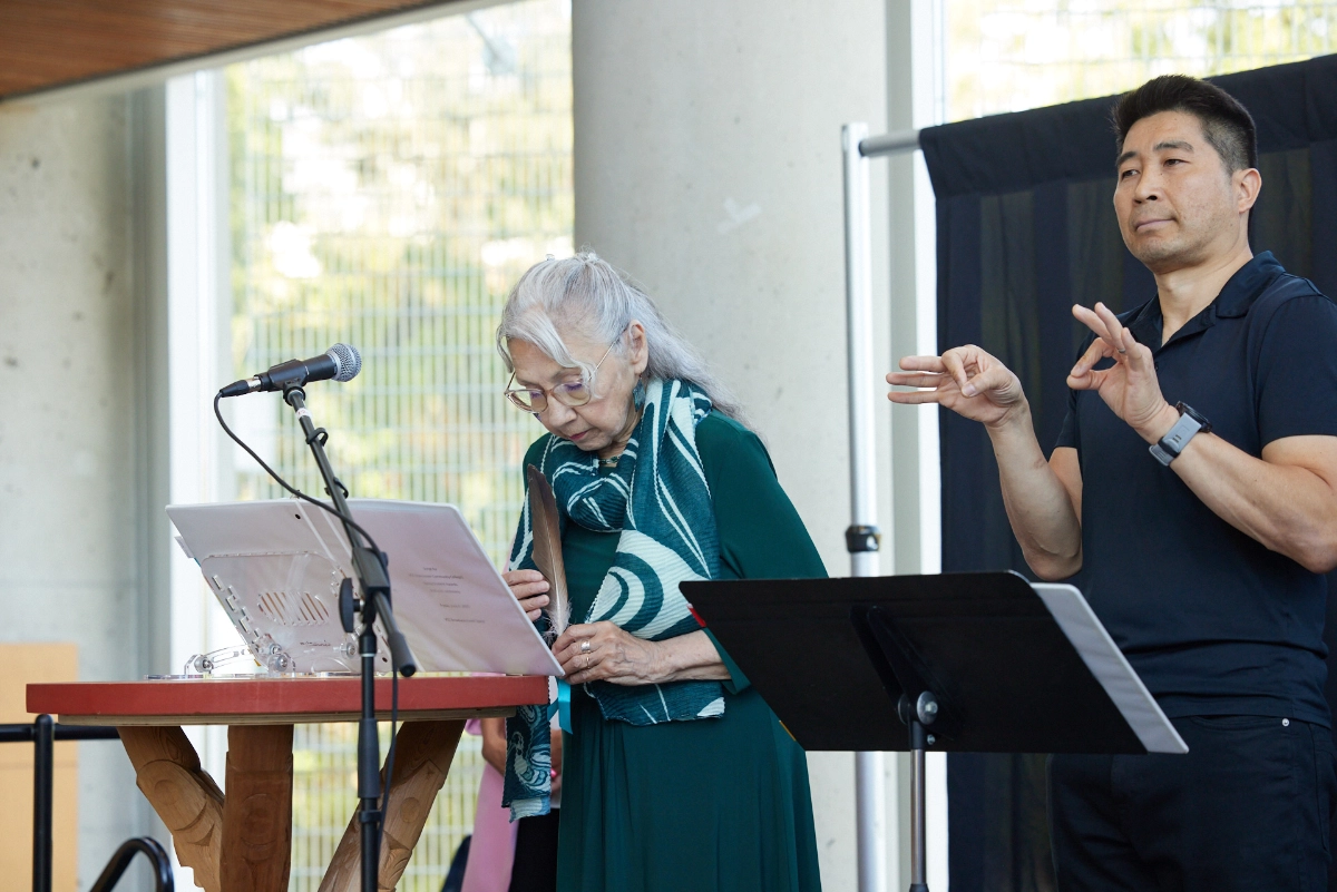 Corporate event photograph of Indigenous elder and sign language interpreter opening event