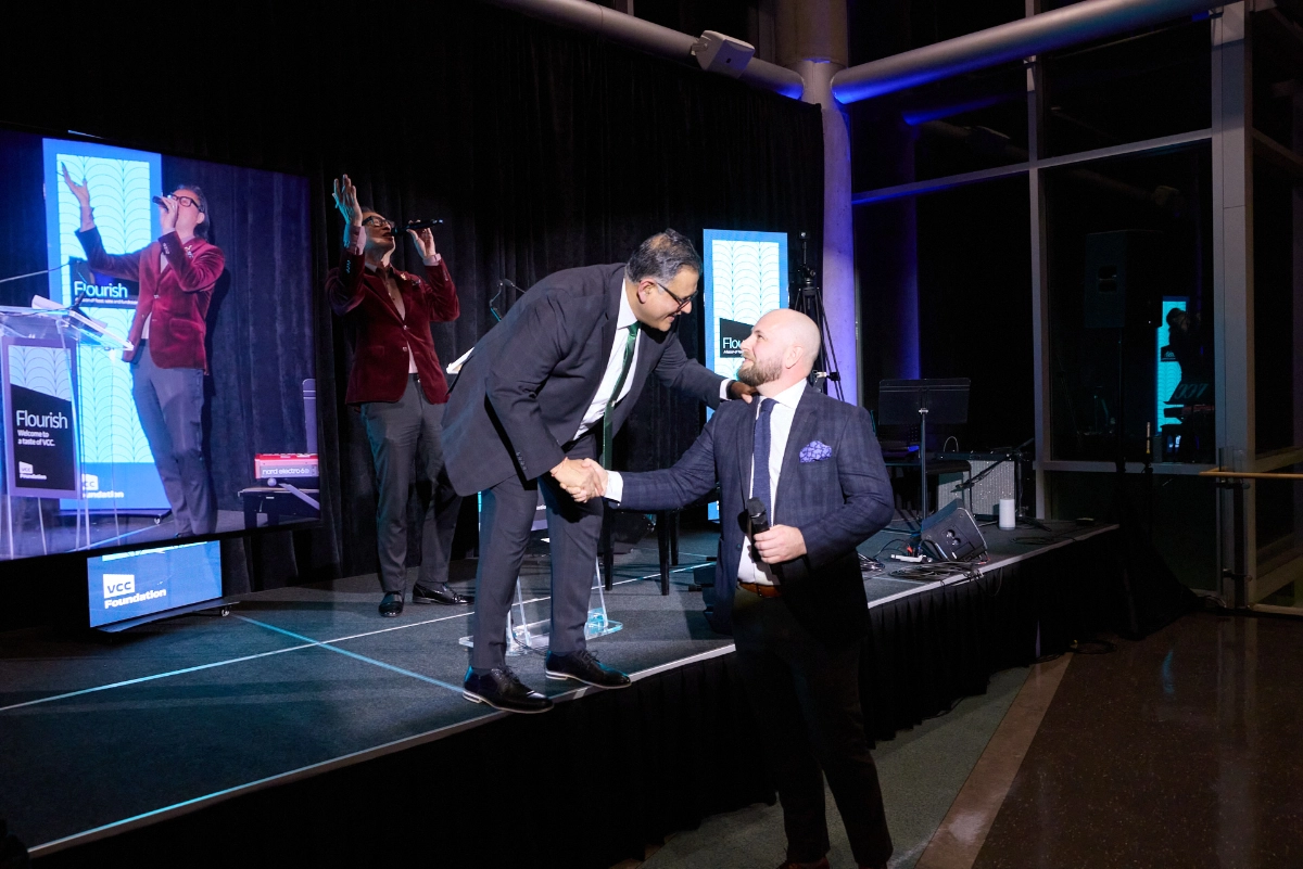 Candid photograph of two shaking hands on stage at corporate event in Vancouver