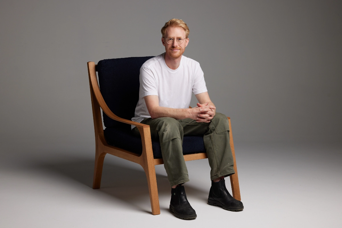 Professional photograph of male woodworker sitting in his chair on a dark grey background taken in a Vancouver photography studio