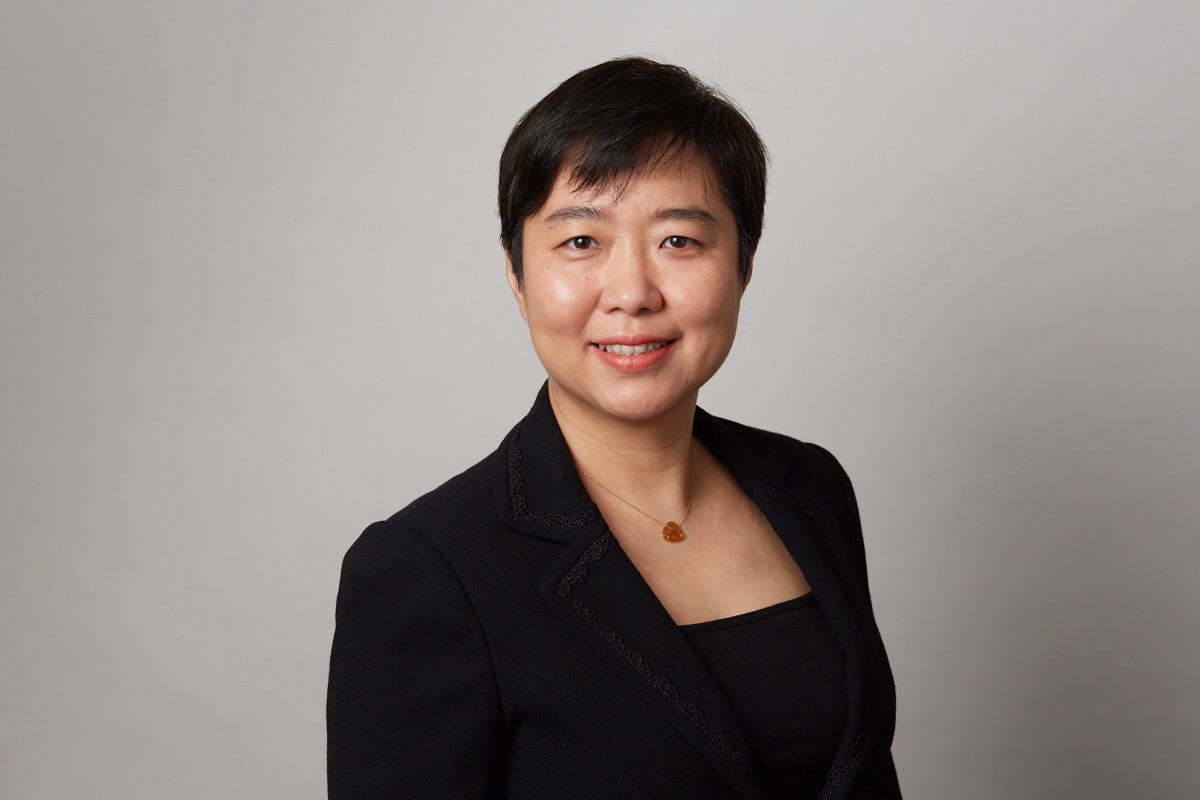 professional corporate headshot of female employee in a black jacket on a dark grey background taken in a downtown vancouver office