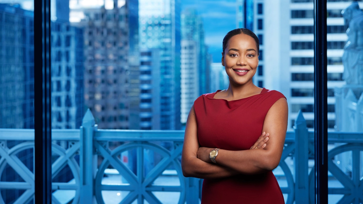 Professional headshot of female lawyer in a burgundy dress with a window view background taken in an office in Vancouver