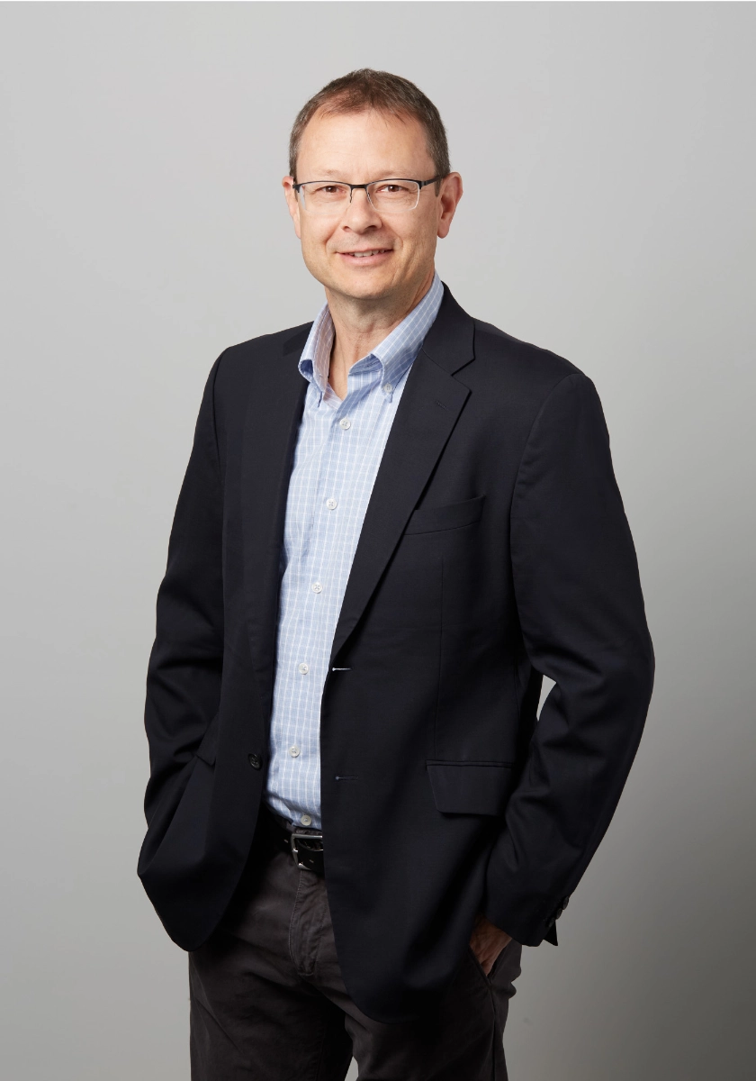Professional photograph of male executive wearing a blue jacket on a grey background taken in a Vancouver office