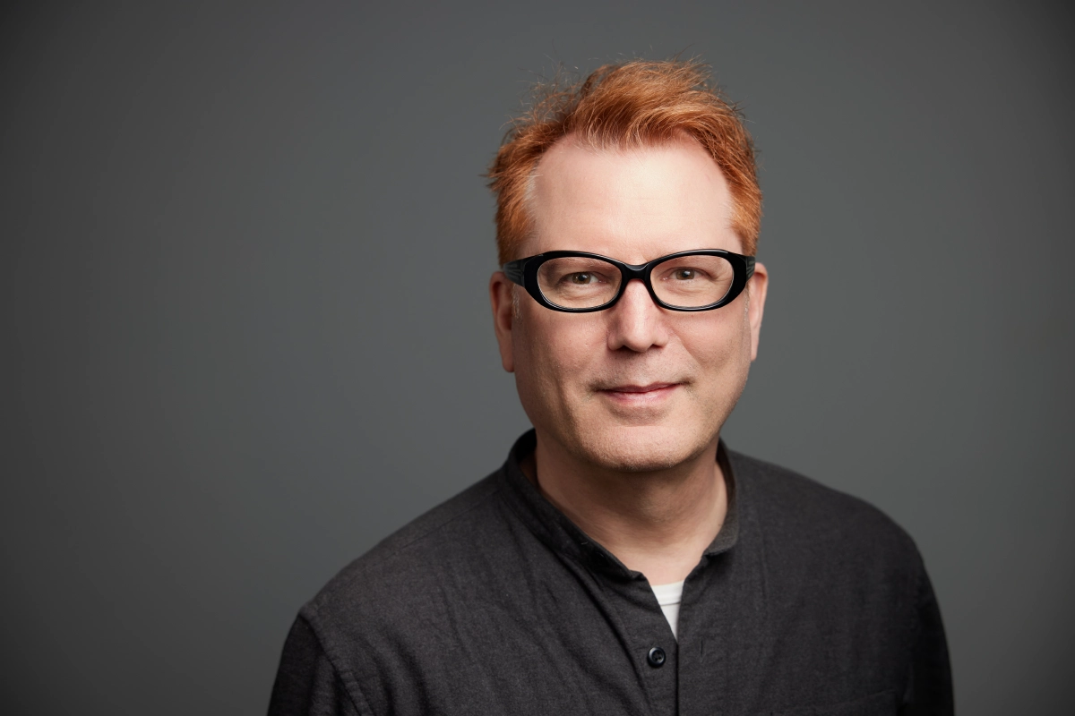 Professional corporate headshot of a male engineer wearing a grey top with a blue-grey background taken in a Vancouver photography studio