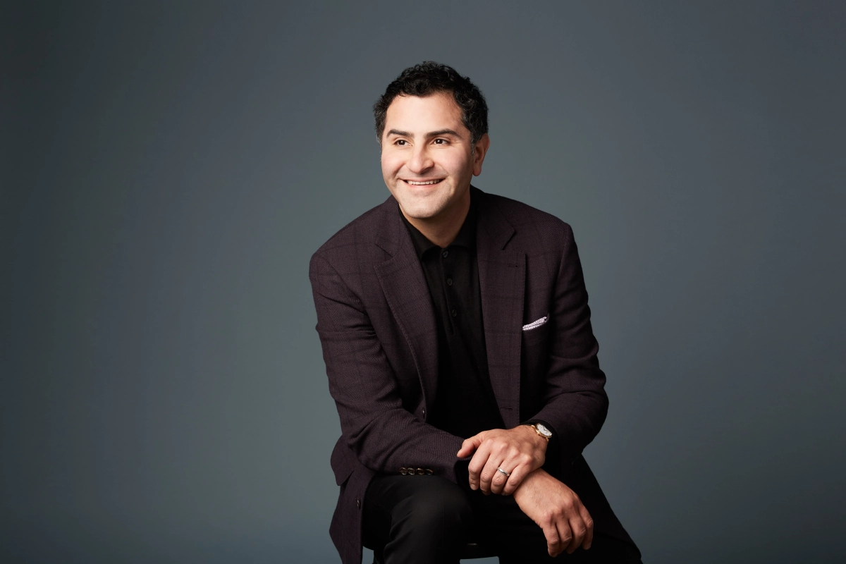 Vancouver corporate headshot of male executive sitting with burgundy jacket with a blue-grey background taken in a Vancouver studio
